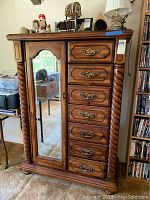 Full view of the wooden wardrobe showing the mirrored door on the left and seven drawers on the right with ornate handles.
