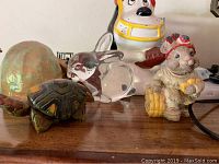 Photo showing figurines including ceramic turtle, glass rabbit, two dog or animal figurines with decorative accents on a wooden surface