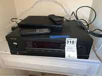 Photo of Sherwood RX-4109 stereo receiver with Samsung DVD player on top showing remote controls and front panel.