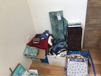 Overall view of two boxes and assorted fabrics on floor showing bolts and folded pieces