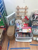 Overview of lot showing wicker basket, plastic bins filled with ribbons, fabric bows, and the wooden spool holder rack.