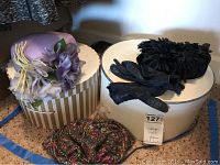 Overview of lavender floral hat, black floral hat with gloves, multicolored knitted hat, and two round hat boxes.