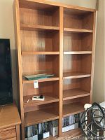Front view of the pair of wood tone book shelves showing the adjustable shelves and wood grain finish.