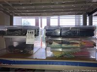 Overview of five clear plastic storage bins stacked on a shelf, containing folded quilting fabric pieces.