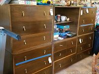 Five matching wooden dresser units; four 3-drawer dressers and one open shelving unit with items on shelves