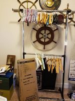 Four metal clothes racks shown, two on display and two in box. Various wooden, plastic, and padded hangers on racks.