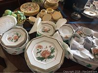 Photo showing stacks of octagonal dinner plates, salad plates, bread plates along with tea cups and saucers arranged on a table.