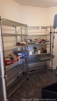 Two metal shelving units set against a wall with various items on the shelves (contents not included in sale). Shelves have grated wire style with chrome finish, size roughly 47x18x75 inches.