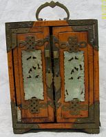 Front view of antique wooden jewelry box with carved jade inserts on doors and ornate metal hardware.