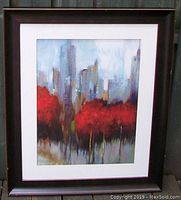 Front view of framed abstract impressionist painting with Toronto cityscape and red trees.