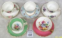 Top view showing five porcelain teacups with matching saucers varying in floral designs and trim colors including green and pink.