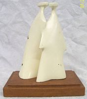 Side angle view showing the two stylized abstract figures and the wooden base