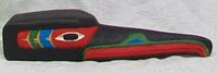Side view of the carved wood Raven totem head showing detailed painted features and carving shape.