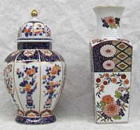 Full view of both lidded urn and vase side by side on white embossed cloth.