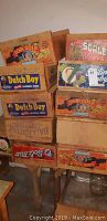Stack of wooden grape boxes showing various brand labels including Lodi Gold, Dutch Boy, Standard Fruit, and others arranged on a wooden stand.