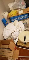 A wide assortment of sewing materials including a Husky Xerocopy box, tissue paper roll, and white fabric or pattern rolls.