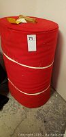 Large red wool bolt standing upright with auction sticker and straps