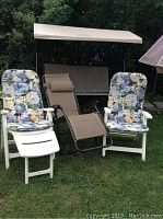 Outdoor patio swing with beige canopy and fabric seat, shown in background on grass.