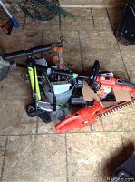 Black and Decker orange and black 2-in-1 grass trimmer and edger, hedge trimmer, and parts on floor