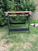 Front view of the Black and Decker Workmate 2000 work bench standing on grass with trees in the background, showing the structure and condition.