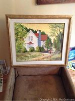 Front view of one framed oil painting featuring a white house in a landscape setting