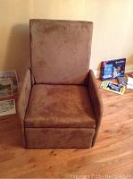 Front view of the brown fabric reclining chair, showing padded armrests and wide seat cushion.