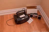 Sony black CD radio cassette recorder with manual on hardwood floor next to small radio clock unit and speakers.