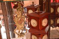 Two decorative clocks displayed: one ornate brass/gold-tone metal clock and one wooden cube clock with four round faces showing different functionalities