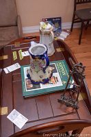 Photo showing the lot items arranged on a wooden coffee table: coffee pot, pitcher, book, and plate stand
