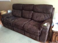 Front view of brown three-seat reclining sofa against wall