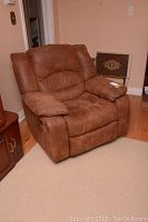 Side angle view of the brown rocker recliner armchair showing plush cushions and suede-like upholstery.