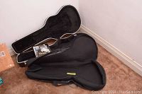 Open view of hard shell guitar case showing velvet-like interior and shape