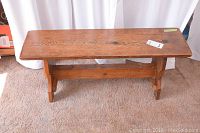 Front view of the solid pine wood bench showing design and wear.