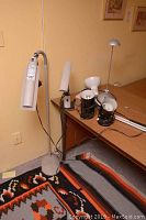 Wide view of all six lamps grouped together, showing the different styles, sizes, and colors. Floor OttLite lamp visible with white body and flexible neck, two black pot lights, and other desk lamps.