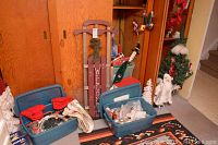 Overview of the lot showing wooden sled, plastic bins with Christmas decorations including ribbons and lights.