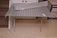 Full view of portable folding table with canvas carrying tote on top.