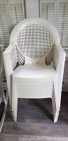 Front view showing 6 white plastic stacking chairs stacked, highlighting the perforated circular backrest.
