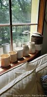 Five stoneware canisters and 4-gallon crock on wooden windowsill near couch