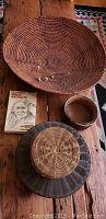 Top view of large grain basket and smaller baskets arranged on wood surface with book titled 'Native American Artifacts'.
