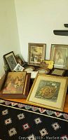 Overview of various framed artworks and decorative items arranged on the floor and leaning against the wall.