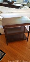 Full view of the wooden side table showing the top surface, two shelves below, and tapered legs.