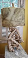 Front view showing driftwood base and artistic abstract lampshade in beige and cream tones.