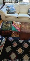 Three carriage blankets placed over couch and stools - various patterns including solid brown, floral with stripes, and abstract floral green design