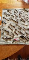 Wide view of over 30 vintage skeleton keys displayed on a woven mat surface on a wooden table