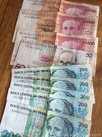 Brazilian paper currency laid out on wooden surface, showing multiple 10,000 Cruzeiros, 200 Cruzeiros, and 50 Cruzeiros banknotes.