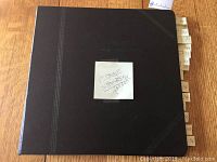 Black vintage stamp album with handwritten note 'Postage stamps only' taped to cover.