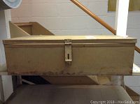 Front view of the rectangular metal storage box showing latch and rust spots.