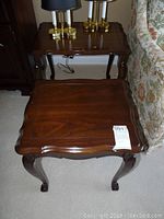 Pair of wooden nesting tables stacked, showing top and carved legs