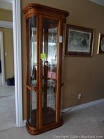 Front view of cabinet showing wood frame, glass door and five display levels