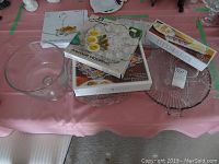 Glass serving dishes and trays on pink tablecloth, with boxed Anchor Hocking deviled egg plate and other serving items.